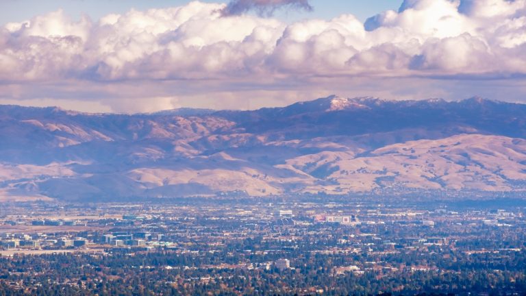 Aerial view of Santa Clara and South San Jose, Silicon Valley, San Francisco Bay Area, California; Diablo mountain range with a dusting of snow covering the peaks visible in the background; cloudy sky