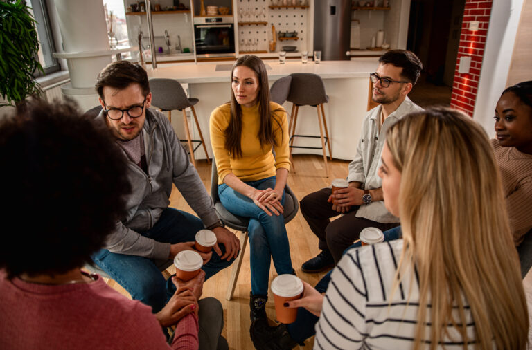 Diverse group of people sitting in circle in group therapy session in residential treatment
