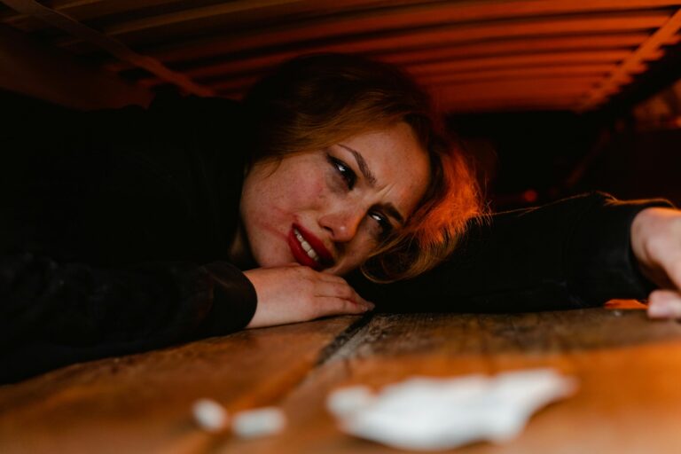 Distressed woman lying on a table near a line of white powder, illustrating the dangers of substance use and addressing the question: is cocaine addictive.